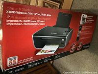 Photo of the front side of the Lexmark X4690 printer box showing the printer image, key features like 'Home & Student', 'Wireless 3-in-1 Print, Scan, Copy', and the red colored packaging.