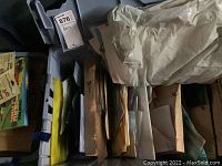 Top view into gray plastic bin containing paper patterns and stained glass sheets.