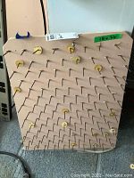 Painted wood thread holder board with nails for holding threads.