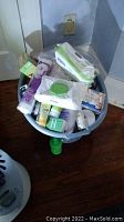 Wide view of various unopened toiletry and beauty products in a blue container showing baby wipes, cotton rounds, hair spray, and boxed hair color.
