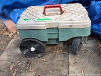 Side view showing beige lid, green body, large black wheels, and red carry handle of resin garden tool cart.