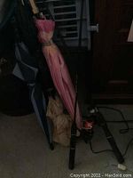 Photo of three umbrellas and two fishing rods leaning against a corner showing overall lot contents and condition.