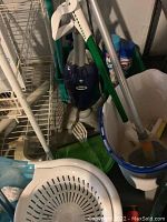 Shark corded steam mop, handheld vacuum, mop buckets, mop heads, and cleaning supplies clustered together