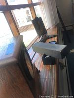 Side view showing clock shape, leather holster, shoe stretcher, and black case on a surface