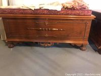 Full view of Lane cedar chest showing the front panel with carved wood detailing and a cushion on top.