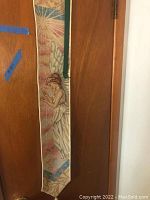 Vertical hanging angel decoration with wings depicted in muted colors, attached to a door or wall.