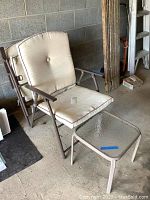 Folding patio chair with beige cushion in garage setting