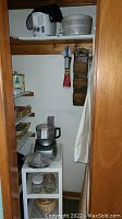 Closet with multiple kitchen items including baskets, food processor, shelves with wicker baskets