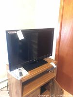 Sony Bravia LCD TV on wooden stand with remote placed on top.