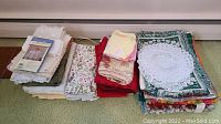 Multiple folded table linens and towels in stacks arranged on the floor, showing variety of colors and patterns.