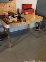 Full view of vintage yellow laminate kitchen table with metal legs and expandable feature, showing items on the tabletop.