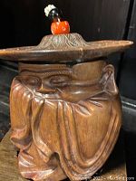 Front and side view of the carved wood monk humidor showing carved details and finial on hat lid.