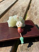 Front view of green jade boy figurine reclining with decorative tassel on rosewood stand