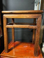 Side view showing table legs and horizontal support bar with carved detail.