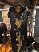 Full view of the black silk Chinese evening robe with dragon and phoenix embroidery