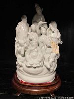Full front view of the white porcelain sculpture atop wood stand