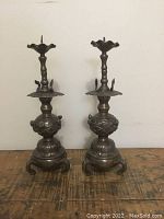Pair of bronze pricket sticks side by side on wooden surface