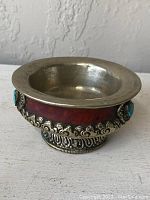 Front angle view of the bowl showing silver metal rim, wood body, ornate silver mounting, and turquoise stones around circumference.