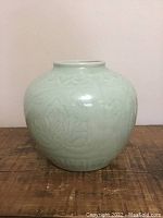 Front view of light green celadon vase showing subtle raised floral pattern on rounded body.