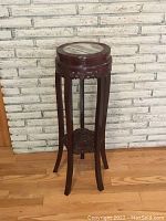 Full view of the Chinese wooden plant stand showing tall slender legs, round marble top, carved apron beneath top, and carved lower shelf.