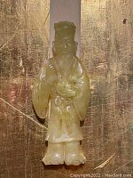 Close-up of the carved jade handle showing intricate details of the figure standing with robe and head-piece.
