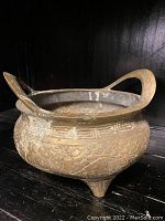 Front and side view of bronze tripod incense burner showing dragon motifs, loop handles, and conical legs.