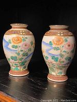 Pair of ceramic vases showing full side view with hand-painted flowers and birds.