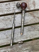 Antique opium pipe with detached spear blade shown side by side on wooden surface.
