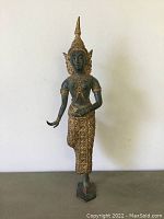 Front view showing green patina and gold gilded decorative details on the figure.