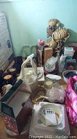 Wide view photo showing various household items including floral wall decor, candle holders, makeup bags, and dishes arranged on a table