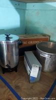 Photo of the lot showing GE electric griddle in box, large stock pot, Westmark coffee urn, and Bondurant wine opener metal case