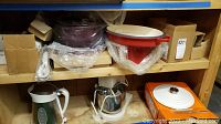 Overview of shelf showing mixer, bowls, pans, pitcher, and can opener