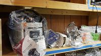 Photo of items on a shelf including the Nuwave Nutri-Pot 8Q digital pressure cooker and other accessories wrapped in plastic bags.