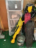 Photo of 4-step ladder still wrapped in bubble wrap and standing upright, five camp chairs in carry bags, and the Eagles tin on the floor showing rust.