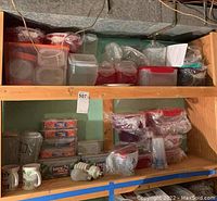 Wide view of storage containers on basement wooden shelves, showing various plastic and glass containers, some wrapped in plastic, with a couple of mugs and light bulbs below.