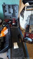 Three power tools including Pop 14.4v saw, drill, and light in a black molded carrying case shown with packaging boxes on floor.