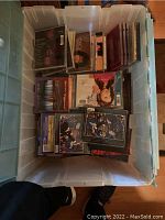 Photo showing top open view of the plastic tote box filled with stacked music CDs, including jewel cases with visible covers like George Michael and others.