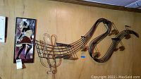Photo shows large metal musical note wall art mounted on wood wall with a treble clef and musical staff design.