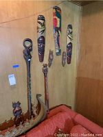 Wall mounted carved wooden African masks in various sizes and colors including red, black, green, beige.