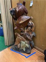 Front view of the carved wood turtle statue, showing multiple stacked turtles with detailed shells and damage to the eyes of the top turtle.