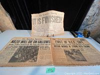 Three vintage newspapers laid out on a table showing headlines about the end of wars from 1918, 1940, and 1946.