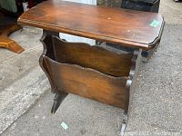 Front and side view of antique walnut magazine end table showing top surface, shaped edges, and magazine rack below.