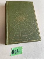 Front cover of the antique book with green hardcover and gold embossed spider web design.
