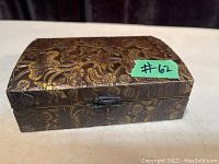 Closed view of embossed metal box showing detailed floral and bird embossing with latch on front.