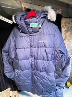 Front view of navy blue Columbia jacket with removable hood displaying puffed quilted design and Columbia logo on chest.