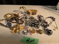 Overview of assorted costume jewelry including bracelets, rings, pendants, and necklaces arranged on a surface in daylight.