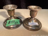 Pair of Birks sterling silver candle holders with labels on base.
