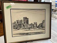 Framed black and white print showing an urban cityscape with buildings and streets, including a visible price tag of $10 on the frame.