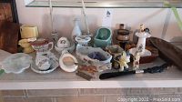 Photo of assorted small ceramic decor items including miniature toilet figurines, lidded bowls, vases, scalloped dishes, and animal figurines arranged on a table.