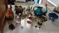 View of all decor items including ceramic pitchers, glass bowl, shakers, figurines, metal tray, and other small decorative pieces on a countertop.